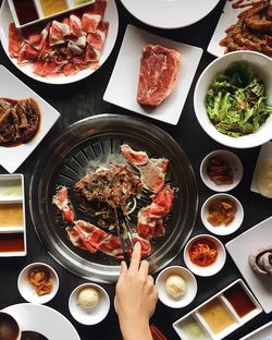 High angle view of hand holding food over hotpot on table