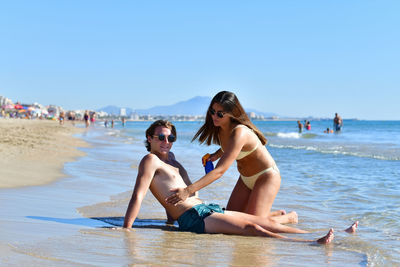 Couple enjoying at beach against sky