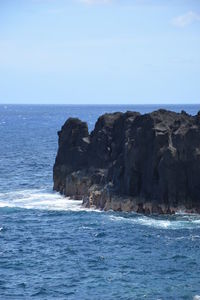 Rock formation in sea against clear sky