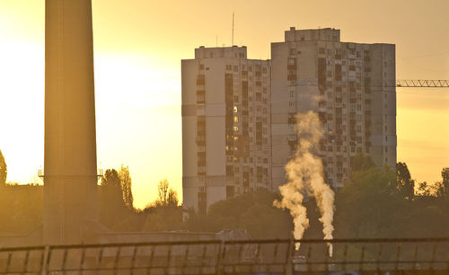 Smoke emitting from factory against sky during sunset