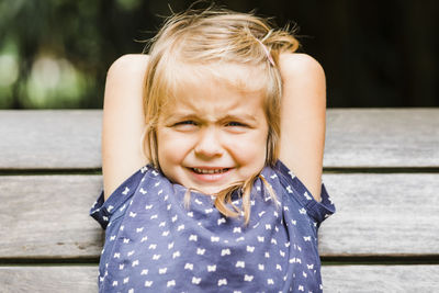 Portrait of cute girl sitting on bench outdoors