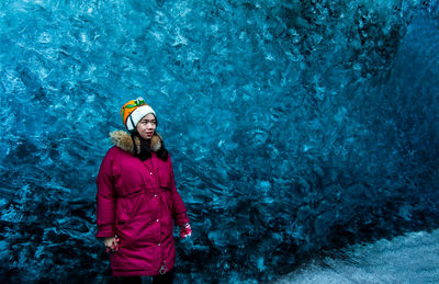 Young woman wearing warm clothing while looking away against ice