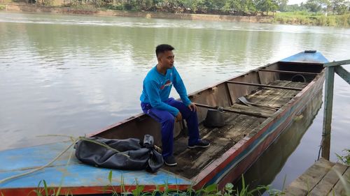 Rear view of man sitting in boat in lake