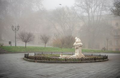 Fountain in park by city against sky