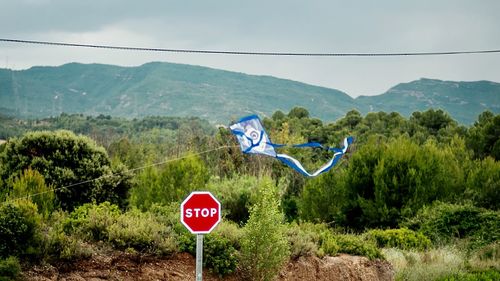 Kite flying over stop sign against mountain