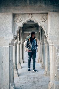 Full length portrait of man standing against building