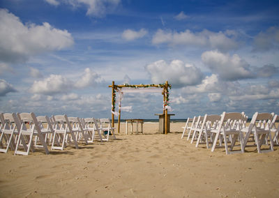 Wedding location on the beach with white chairs and a cloudy sky