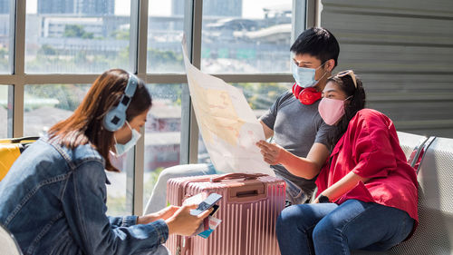 Couple wearing mask looking at map while sitting at airport