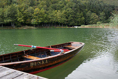 Boat moored on lake against trees