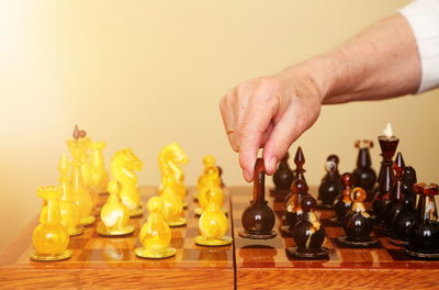 Cropped hand of man playing chess against wall