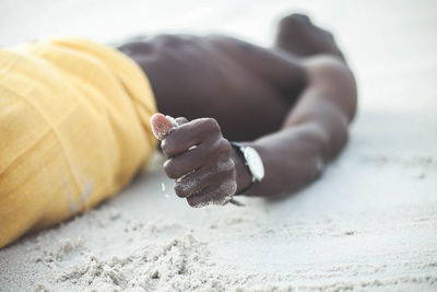 Close-up of hand on sand at beach