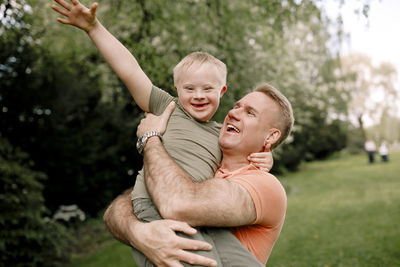 Happy man carrying son with down syndrome at park