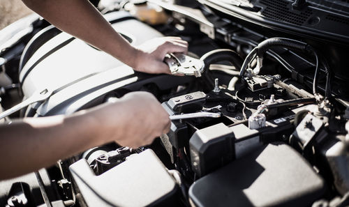 Cropped hand of mechanic repairing car engine in workshop