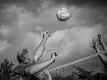 Low angle view of men playing with ball against sky