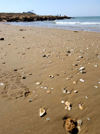 Footprints on sand at beach against sky