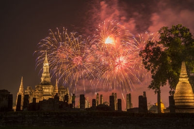 Firework display over illuminated buildings in city at night