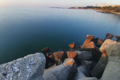 Rocks by lake against sky