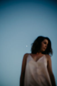 From below side view of blurred thoughtful woman relaxing on amazing blue sky at dusk