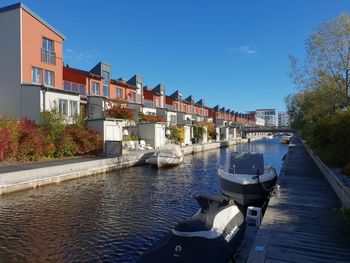 Boats moored in canal amidst buildings against sky