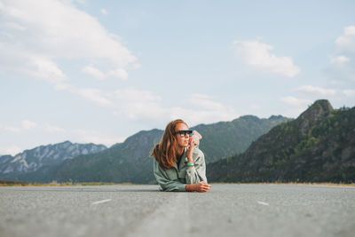 Beautiful smiling young woman traveler in casual clothes on road, trip to mountains, altai