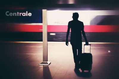 Rear view of silhouette man standing in bus
