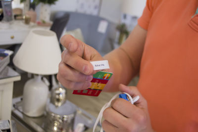 Midsection of man holding credit card at home