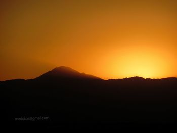 Scenic view of silhouette mountains against orange sky