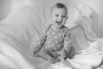 Baby boys sitting on bed at home