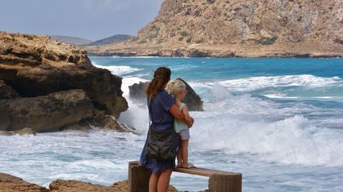 Rear view of mother with child at seashore