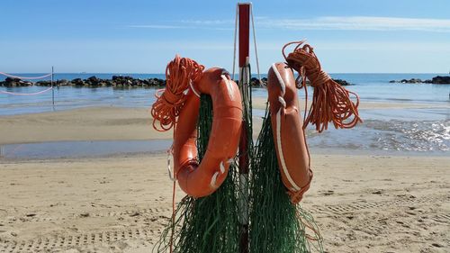 Rescue equipment hanging on pole at beach against sky