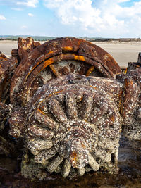 Close-up of rusty wheel against sky