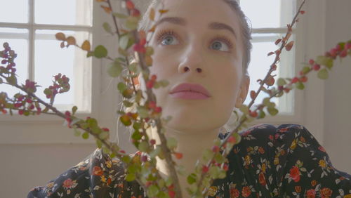 Portrait of woman with red flowers against wall