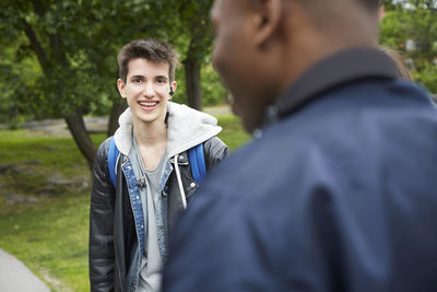 Portrait of smiling teenage boy standing at park