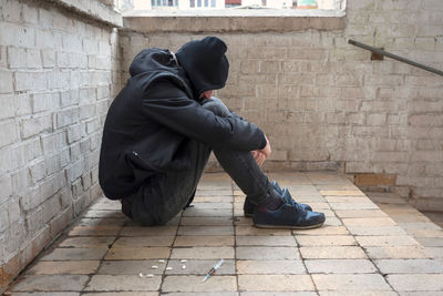 Rear view of man sitting on footpath