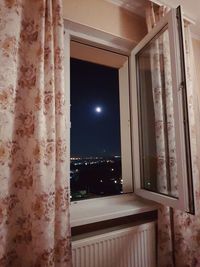 Illuminated building seen through window of house