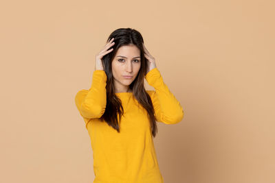 Portrait of a young woman against yellow background