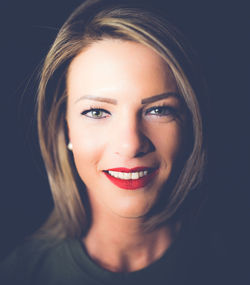 Close-up portrait of young woman smiling in darkroom