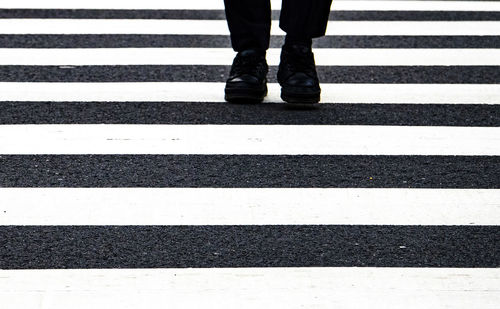 Low section of man standing on zebra crossing