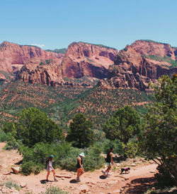 Group of people on rock formation against clear sky