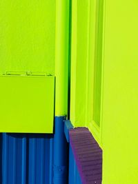 Close-up of yellow door on green wall