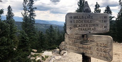 Information sign on mountain against cloudy sky