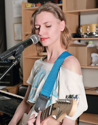 Young woman rock musician playing guitar in rehearsal room. vertical shot of female guitarist 