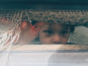 Close-up of girl looking through covered fabric