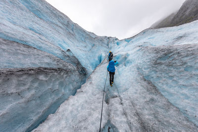 Rear view of man walking on snowy mountain