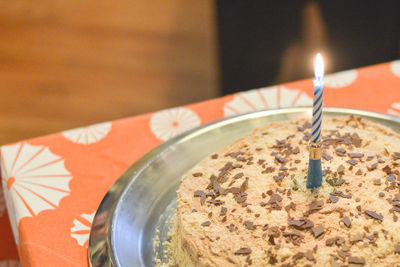 Lit candle on cake at table