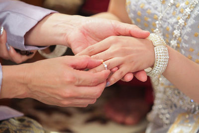 Midsection of wedding couple exchanging finger rings during ceremony