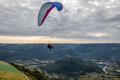 Low angle view of person paragliding against sky