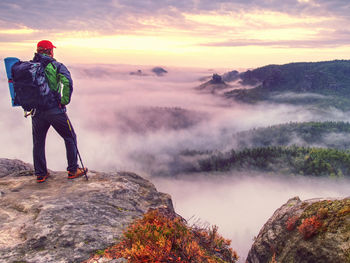 Man observe fall daybreak on peak of rock empire. dreamy foggy landscape of saxony switzerland park