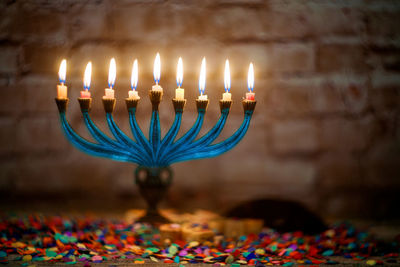 Close-up of illuminated candles on menorah against wall