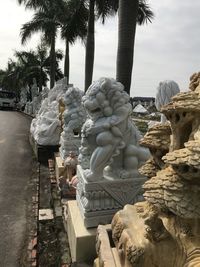 Statue and palm trees against sky